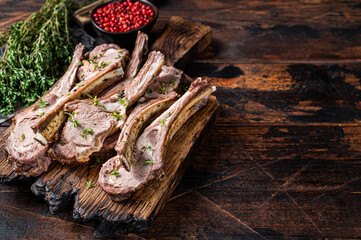 BBQ Grilled Lamb Ribs Chops steaks on butcher board with meat cleaver. Dark wooden background. Top view. Copy space