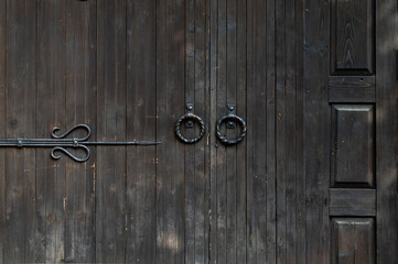 Old wooden doors with round forged handles. Plane rusted wooden door. Forged staff elements.