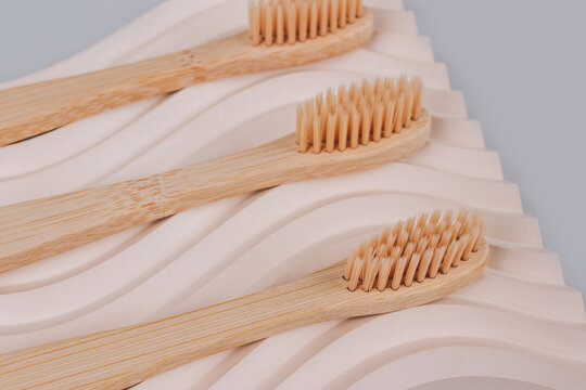 Set of natural bamboo toothbrushes on biege plaster mold against gray background with copy space. Sustainable lifestyle, zero waste home. Selective focus. Mockup image
