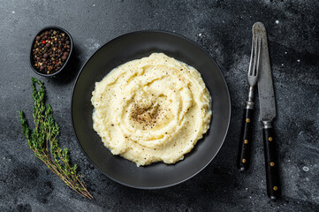 Potato puree, Mashed potatoes  in a plate with herbs. Black background. Top view