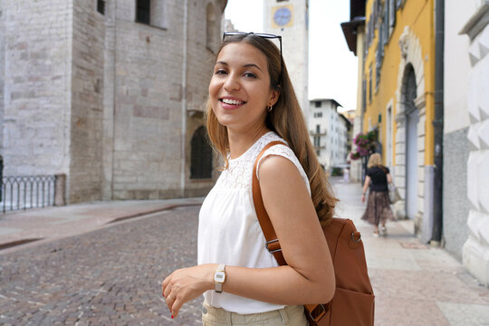 Happy smiling tourist woman visiting the old medieval town of Trento, Italy
