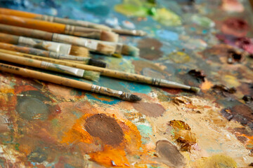 Tubes of oil paint, palette and artist paintbrushes closeup.