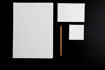 white papers and pencil on black background
