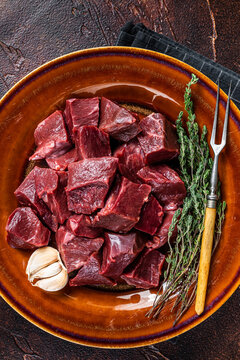 Cut Beef or veal raw heart in a rustic plate with herbs. Dark background. Top View