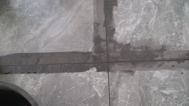 Grouting ceramic tiles. Tilers filling the space between tiles using a rubber trowel. Grouting after laying ceramic tiles on the floor.