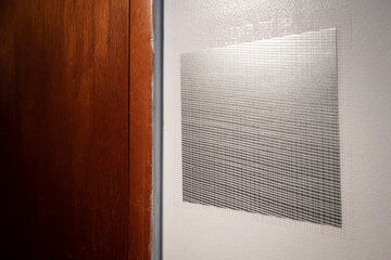 Metal and mesh drywall patch applied to cover hole, ready for coverage with spackling compound