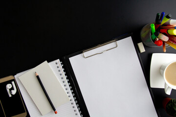 phone, note papers, notebook, coffee and colored pencils on black background