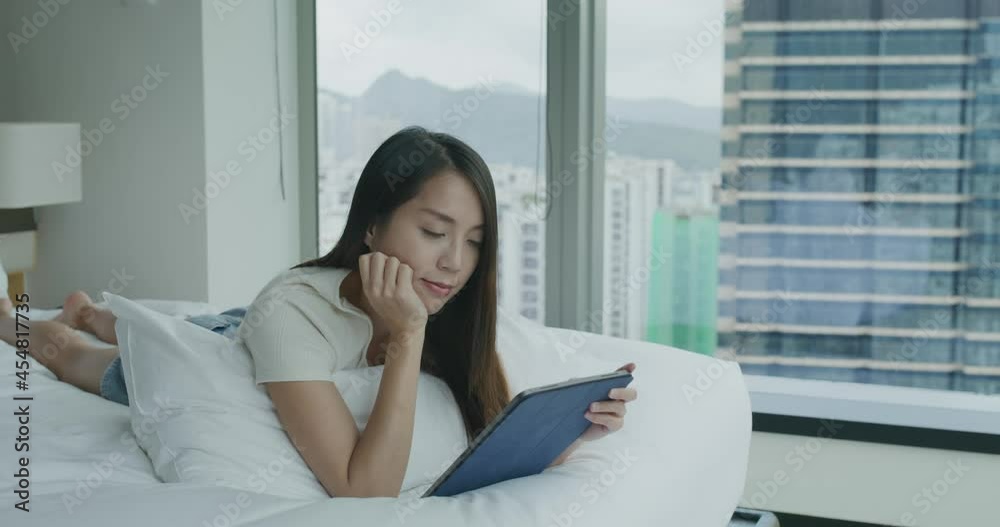 Poster woman use of tablet computer and lying on bed