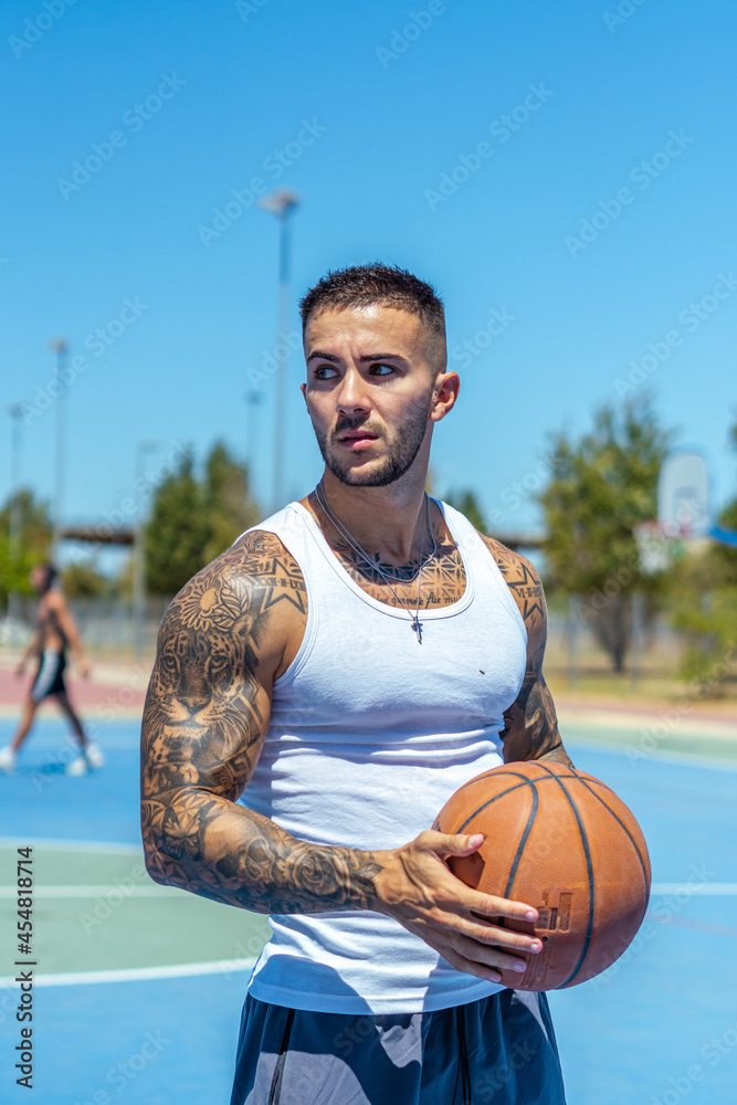 Sticker vertical shot of a sporty caucasian male with tattoos playing basketball