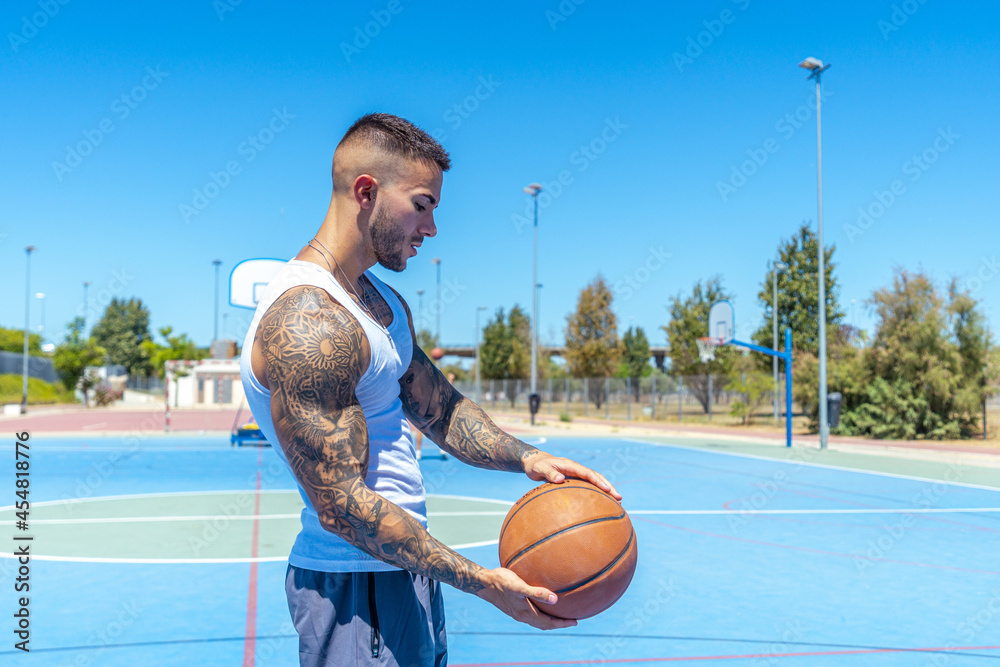 Wall mural view of a sporty caucasian male with tattoos playing basketball