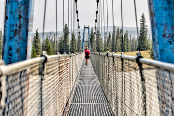 Mother and son hiking along a bridge crossing the South Saskatchewan River in the Nordegg Region of the Canadian Rocky Mountains - obrazy, fototapety, plakaty