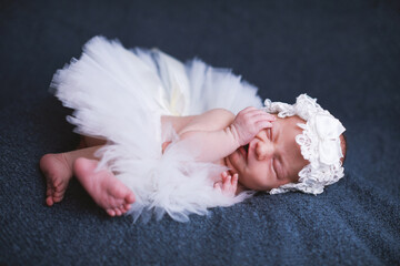 Sleeping newborn baby wearing ballet tutu and headband.