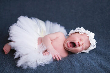 Sleeping newborn baby wearing ballet tutu and headband.