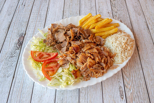 Kebab tray with mixed roast chicken and lamb meat garnished with white rice, French fries and lettuce and tomato salad