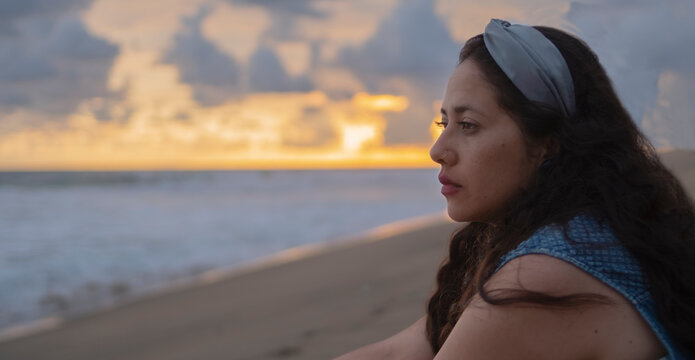 Retrato de joven mujer latina contemplando serena el atardecer en la playa. Pie de la Cuesta, Acapulco, México. 