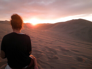 Fototapeta na wymiar Woman looking at the sunset in a desert.