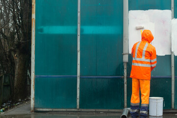 The worker cleans the wall from the inscription. Vandal graffiti cleaning.