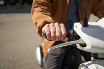 Close-up of the motorcyclist's hand. The concept of speed, movement, forward motion, acceleration, transportation in the city. A male hand turns the throttle of an urban motorcycle.