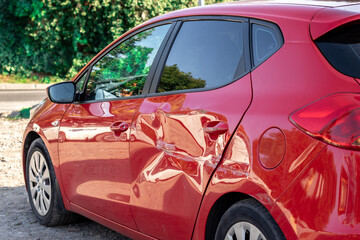red car hatchback with a dent after an accident - obrazy, fototapety, plakaty