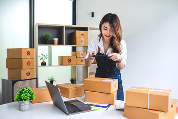 Fototapeta na wymiar businesswoman start small business and successful SME entrepreneurs A woman works from home delivering parcels online. SME delivery concept and packaging