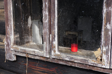 Old glass window with peeling frame and red candle.