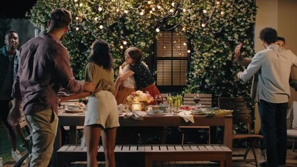 happy friends arriving at dinner party celebration hugging enjoying friendship reunion gathering sitting at table with healthy food sharing weekend together on beautiful summer night 4k