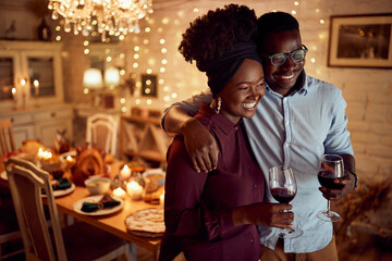 Embraced African American couple drinks while celebrating Thanksgiving at home.