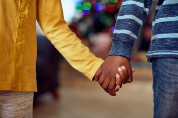 Close-up of African American boy and girl holding hands on Christmas day at home.
