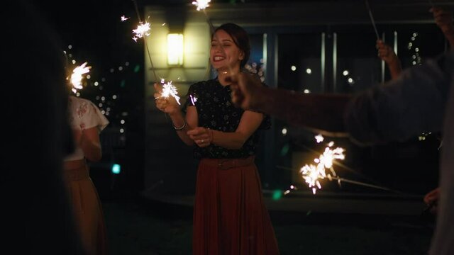 happy group of friends celebrating with sparklers smiling enjoying new years eve together sharing holiday celebration on peaceful evening at home in backyard 4k