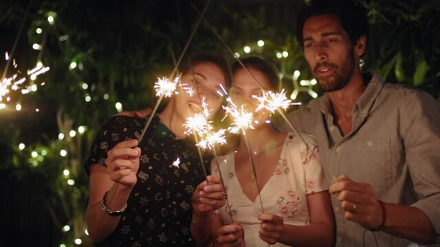 happy group of friends celebrating with sparklers smiling enjoying new years eve together sharing holiday celebration on peaceful evening at home in backyard 4k