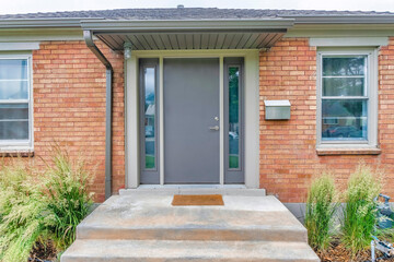 Modern gray front door with two side panels and mailbox on the side