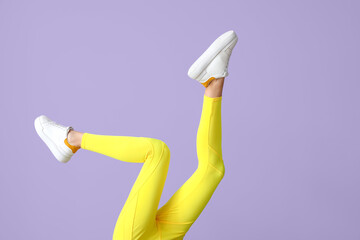 Legs of sporty young woman in leggings on color background