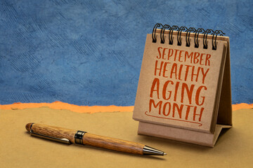 September - Healthy Aging Month, handwriting in a small desktop calendar against abstract paper landscape, health and lifestyle concept