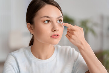 Young woman putting in contact lenses at ophthalmologist's office