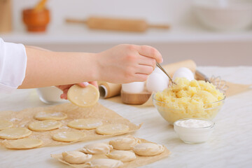 Woman preparing tasty dumplings on kitchen table