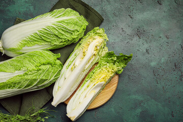 Board with fresh chinese cabbage on color background