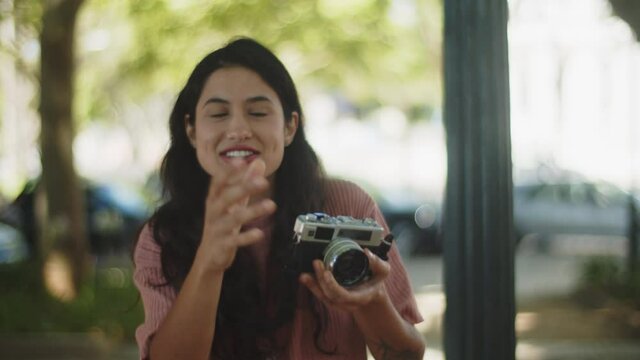 Smiling Caucasian woman taking picture with enthusiasm. Happy girl with camera pressing shutter button, taking photos from different angles, working outside in summer. Photography, occupation concept 