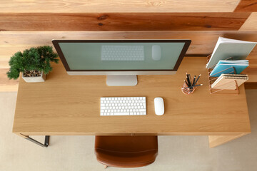 Modern workplace with computer near wooden wall