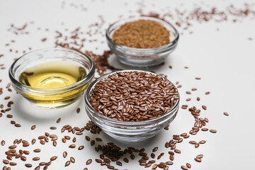 Bowls with flax seeds and oil on light background, closeup