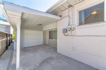 Small garage at the side of a house with white siding and two electricity meters