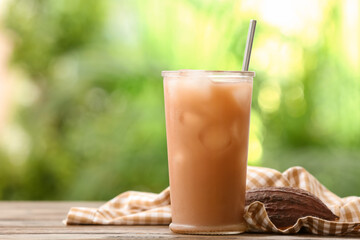 Glass of tasty chocolate milk on table outdoors, closeup