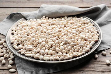 Plate with raw beans on wooden background