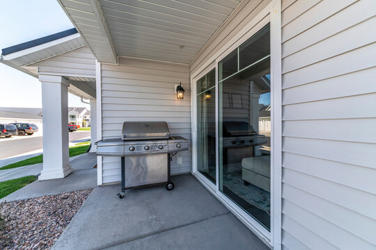 Steel Burner Gas Barbecue Grill Under The Lamp Outside The House With Vinyl Wall Siding