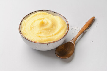 Bowl of tasty mashed potatoes with garlic on light background