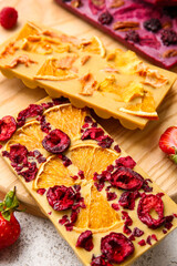Handmade chocolate bars with fruits and berries on light background, closeup