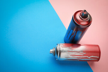 Used cans of spray paints on color background, space for text. Graffiti supplies