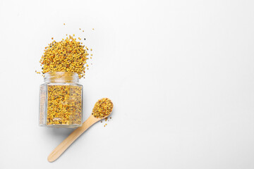 Jar and spoon with bee pollen on light background