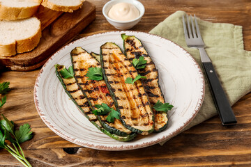Plate with tasty grilled zucchini on wooden background