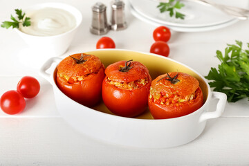 Baking dish with tasty stuffed tomatoes on light background