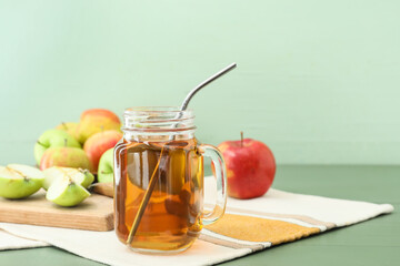 Mason jar of tasty apple juice on color wooden background